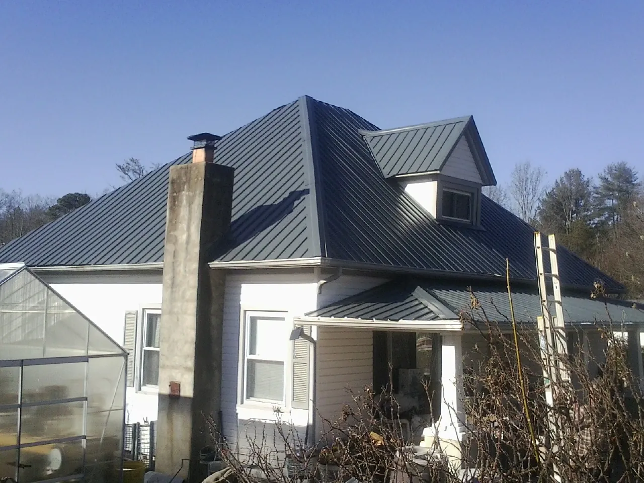 Dark blue standing seam metal roof on a white farmhouse with dormer — Slate & Tile Roof Repair by Roofing Brothers in Springbrook