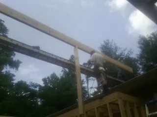 Carpenter setting a ridge beam over a new addition frame — Ice Dam Removal by Roofing Brothers in Springbrook