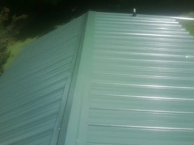 New green metal panels meeting at the ridge of a roof — Flat Roof Repair work by our crew in Springbrook