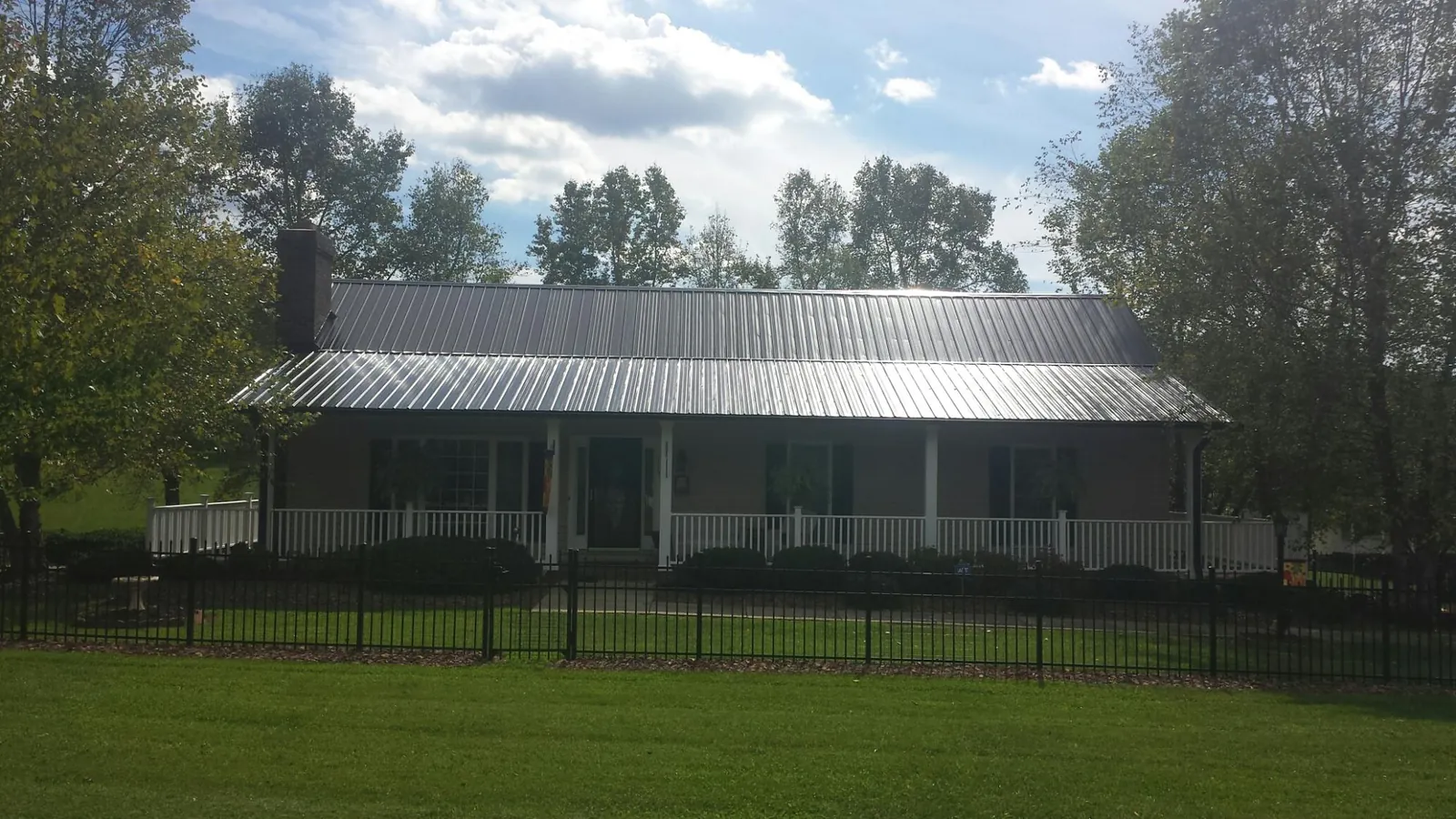 Gray metal roof on a brick ranch with a full width front porch — Gutter Guard Installation work by our crew in Springbrook