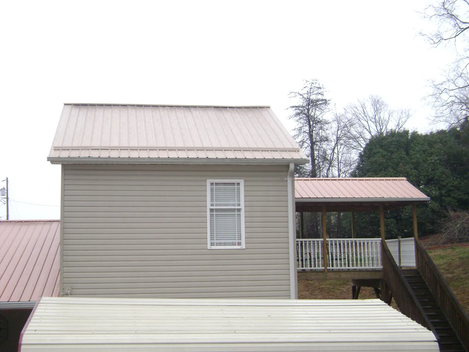 Tan metal roofs on a two story addition and attached porch, from a Roof Replacement job in Springbrook